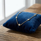 Artistic scene in a light studio showing a tiny 1 CT TW lab-grown diamond necklace on a velvet cushion, emphasizing craftsmanship.